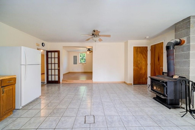 unfurnished living room with ceiling fan, a wood stove, and electric panel