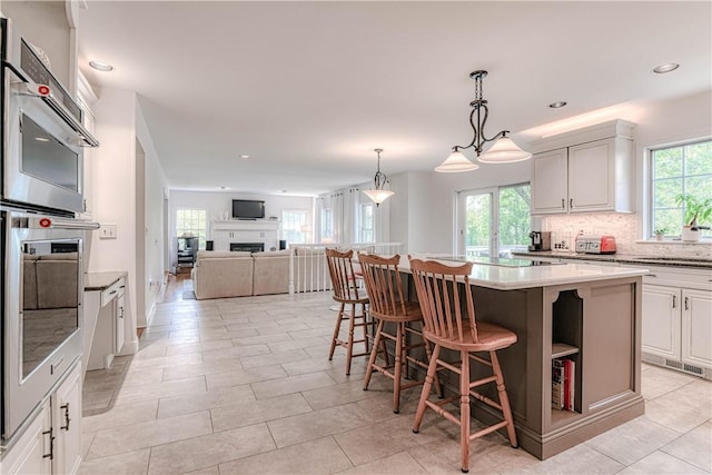 kitchen with a breakfast bar area, white cabinetry, backsplash, and a center island