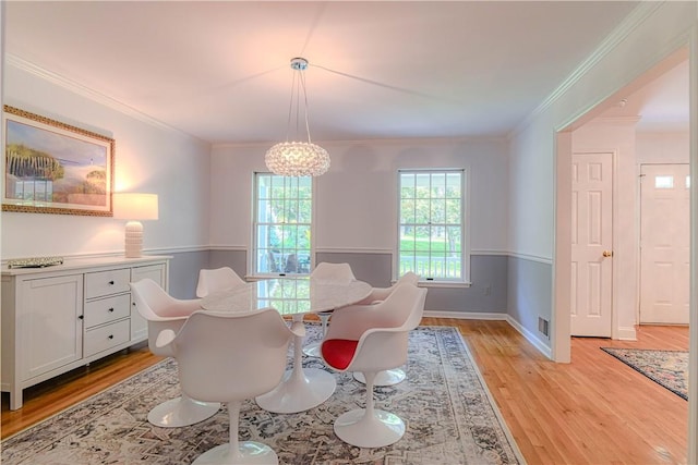 dining area featuring light hardwood / wood-style floors, ornamental molding, and a chandelier