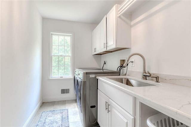 laundry area with washing machine and dryer, cabinets, plenty of natural light, and sink