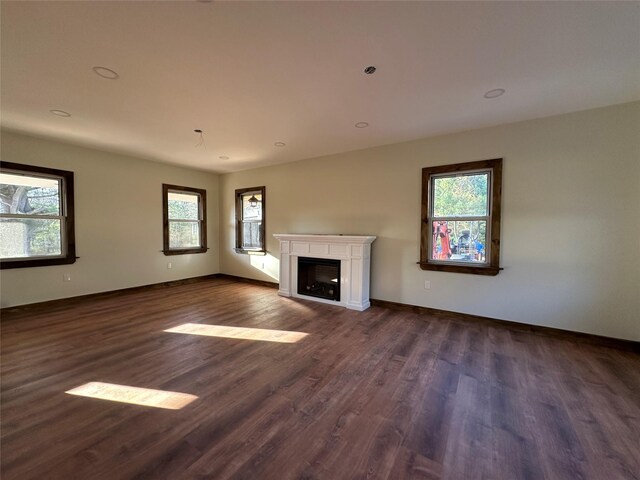 unfurnished living room with a fireplace, baseboards, and dark wood-style floors