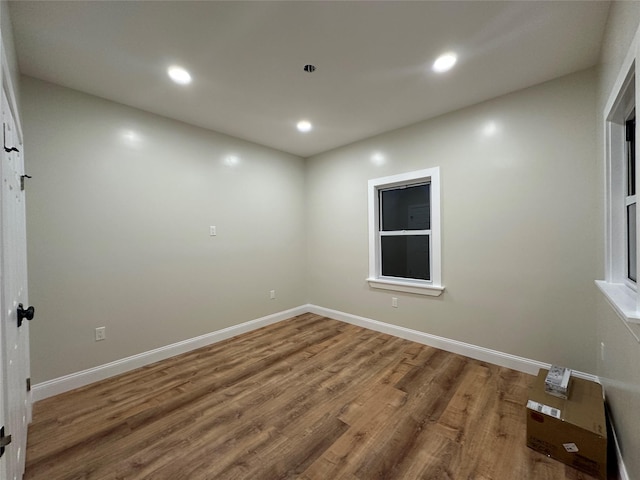 spare room with baseboards, wood finished floors, and recessed lighting