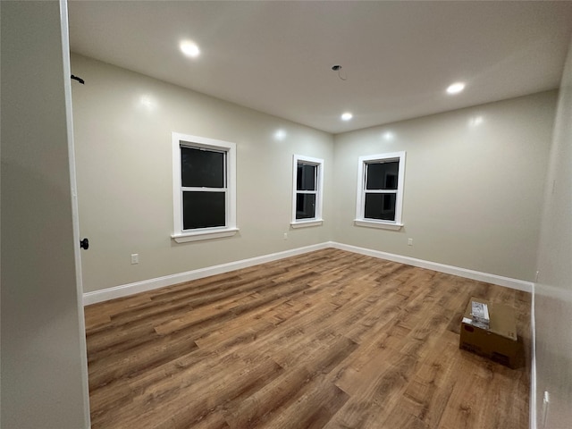 empty room with recessed lighting, wood finished floors, and baseboards