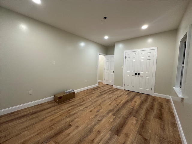 interior space with baseboards, wood finished floors, and recessed lighting