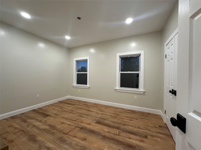 unfurnished room featuring baseboards, wood finished floors, and recessed lighting