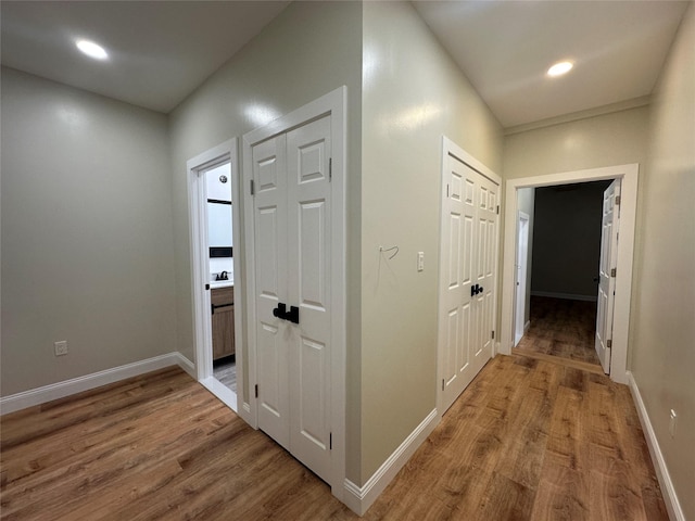 corridor with baseboards, wood finished floors, and recessed lighting