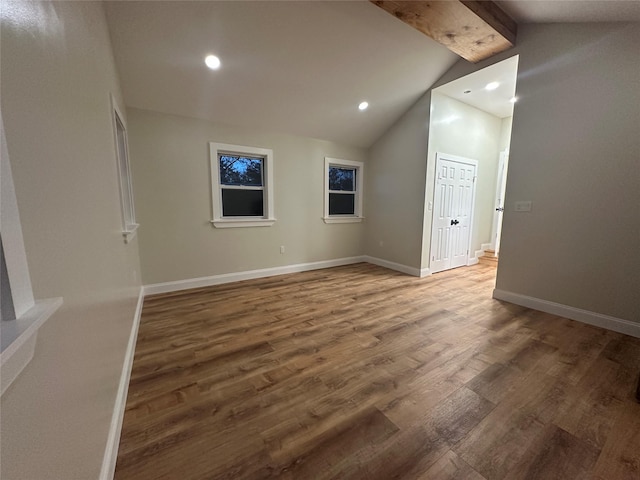empty room featuring lofted ceiling with beams, baseboards, wood finished floors, and recessed lighting