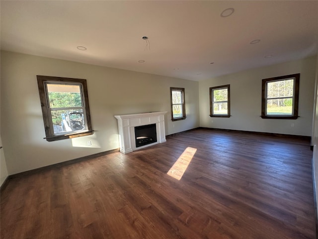 unfurnished living room with a fireplace, dark wood finished floors, and baseboards