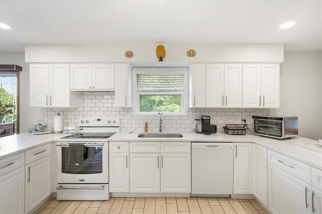 kitchen featuring a wealth of natural light, white cabinetry, sink, and white appliances