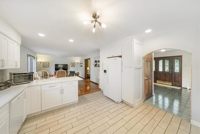 kitchen with kitchen peninsula, white cabinets, light hardwood / wood-style floors, and white appliances