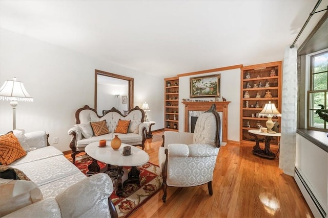 living room featuring light hardwood / wood-style flooring, built in features, and a baseboard heating unit