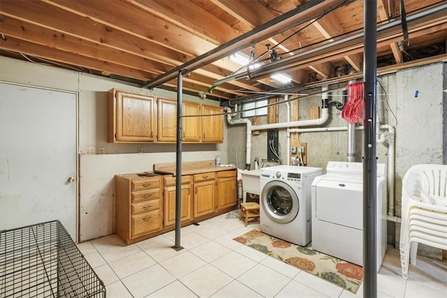 clothes washing area featuring cabinets, washing machine and dryer, sink, and light tile patterned flooring