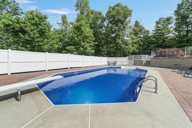 view of swimming pool with a diving board and a patio area