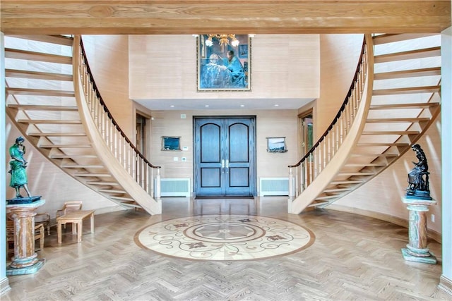 entryway with a towering ceiling and light parquet flooring