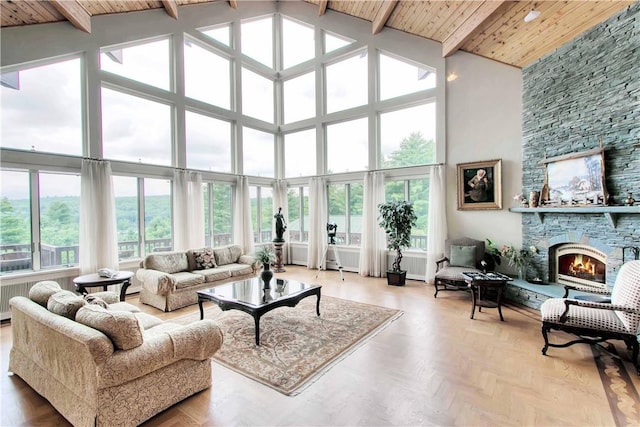 living room featuring wood ceiling, light parquet floors, high vaulted ceiling, a stone fireplace, and beamed ceiling