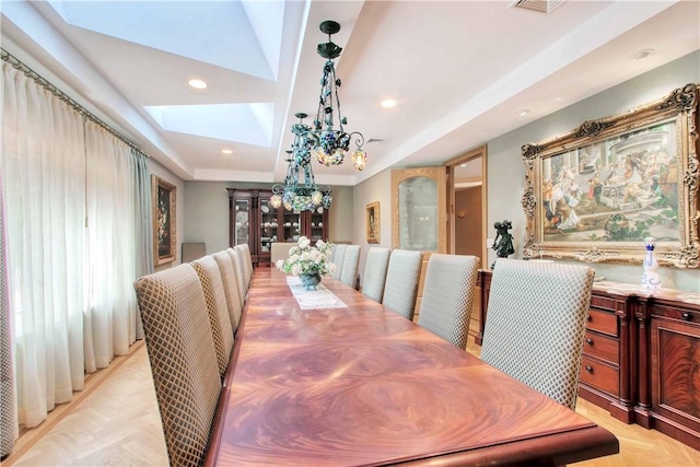 dining area featuring a skylight, a raised ceiling, and light parquet flooring