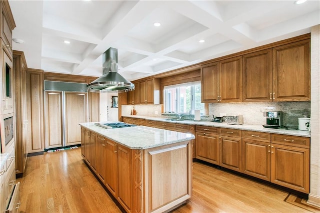 kitchen with island range hood, a center island, built in appliances, light stone counters, and light wood-type flooring