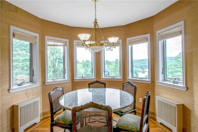 dining space with radiator, light parquet flooring, and a chandelier