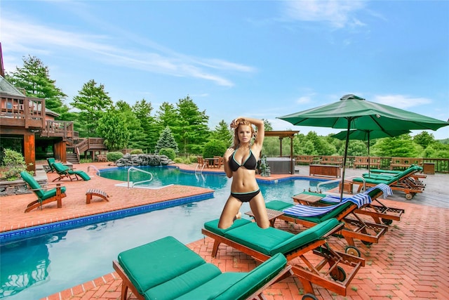 view of swimming pool featuring a wooden deck, a jacuzzi, and a patio