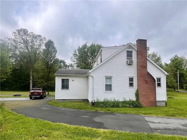 view of property exterior with cooling unit and a lawn