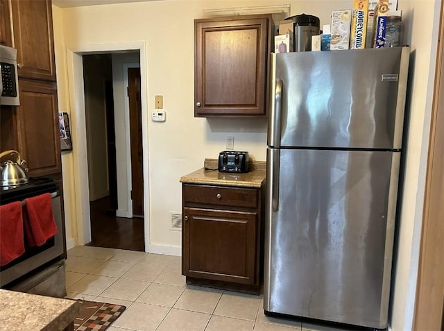 kitchen featuring dark brown cabinets, light tile patterned floors, and appliances with stainless steel finishes