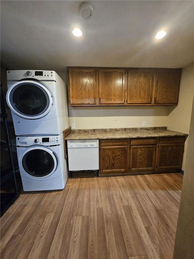 washroom with stacked washing maching and dryer and wood-type flooring