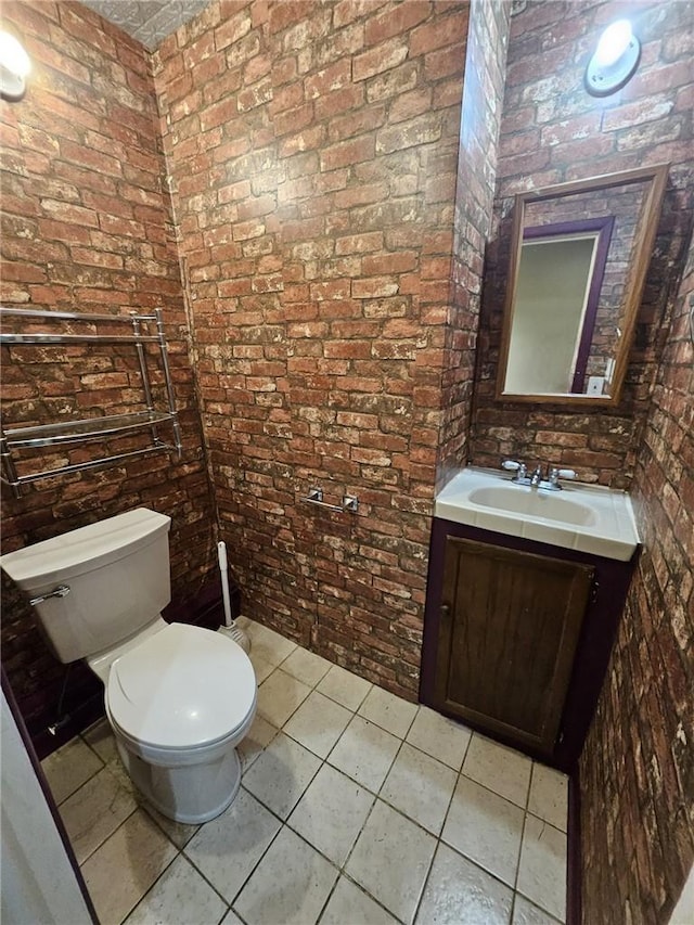 bathroom featuring tile patterned floors, brick wall, and toilet