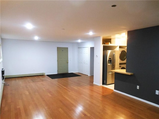 unfurnished room featuring light hardwood / wood-style floors and stacked washer / drying machine