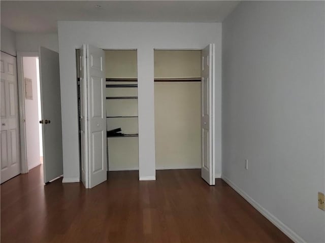 unfurnished bedroom with dark hardwood / wood-style flooring and two closets