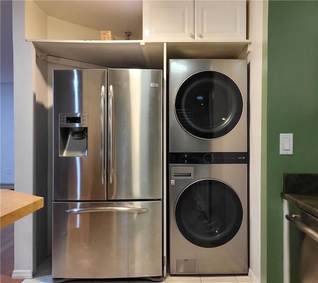 laundry area with stacked washer / dryer and light tile patterned floors