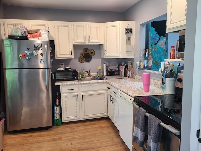 kitchen with light stone countertops, stainless steel appliances, sink, light hardwood / wood-style flooring, and white cabinetry