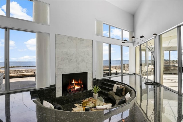 living room with a healthy amount of sunlight, a water view, and a high ceiling