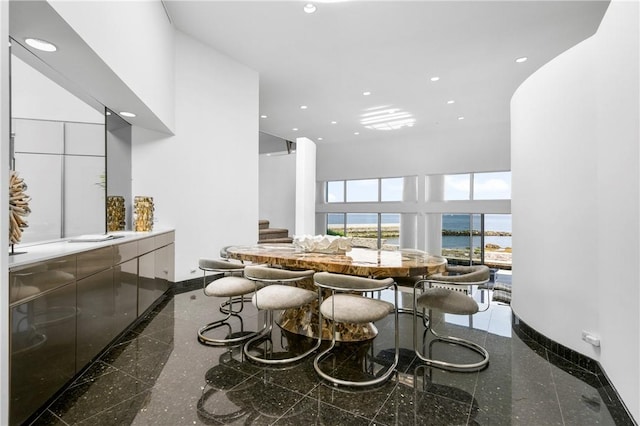 dining space with a water view and a high ceiling