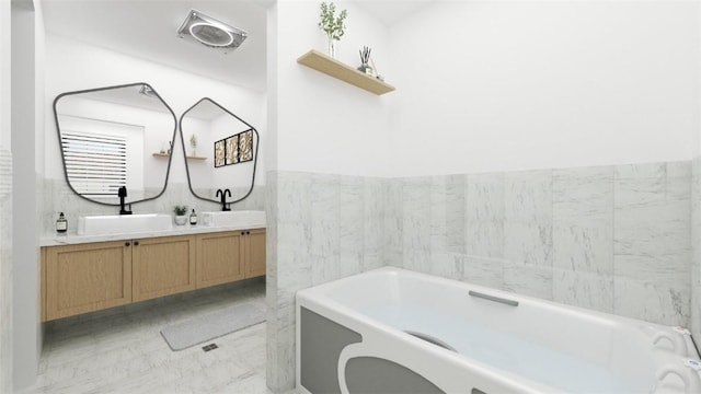 bathroom featuring vanity, a tub to relax in, and tile walls