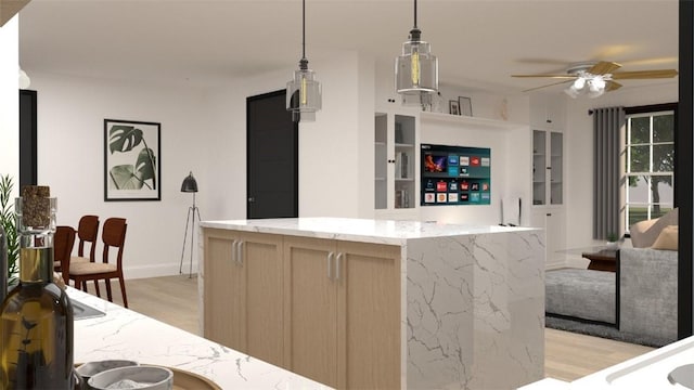 kitchen with light stone countertops, pendant lighting, light wood-type flooring, and light brown cabinetry