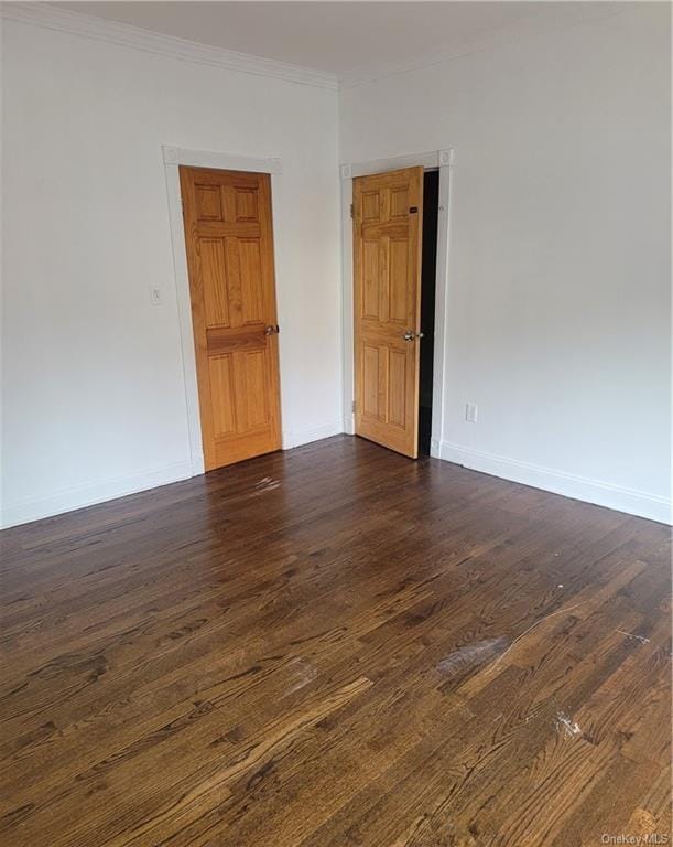 unfurnished room with ornamental molding and dark wood-type flooring