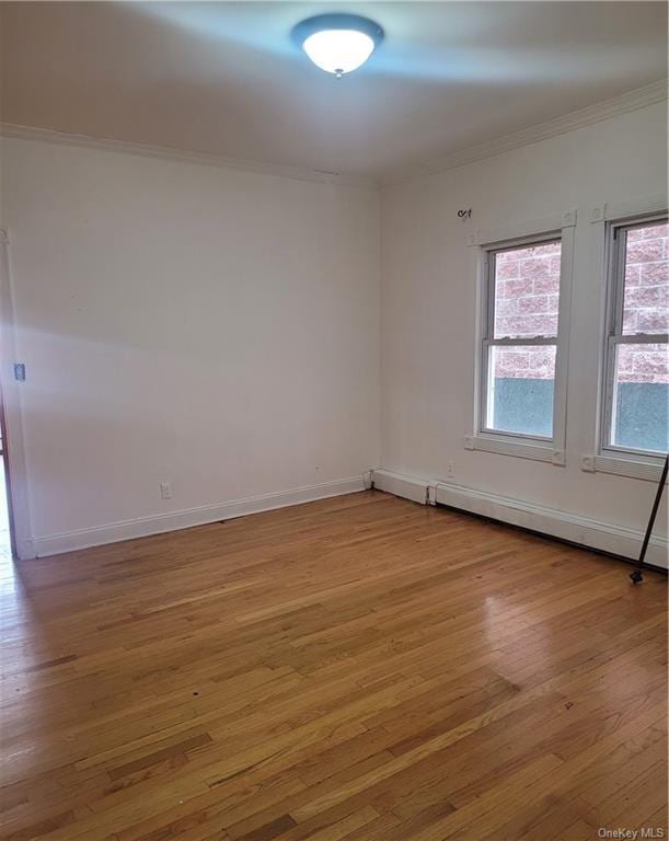 spare room with baseboard heating, hardwood / wood-style floors, and ornamental molding