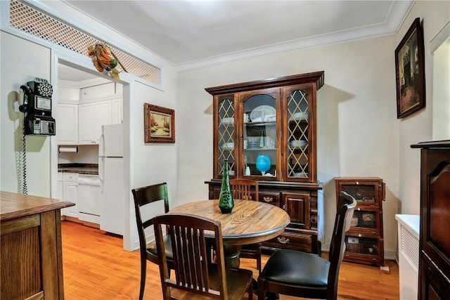 dining area featuring light wood-type flooring and crown molding