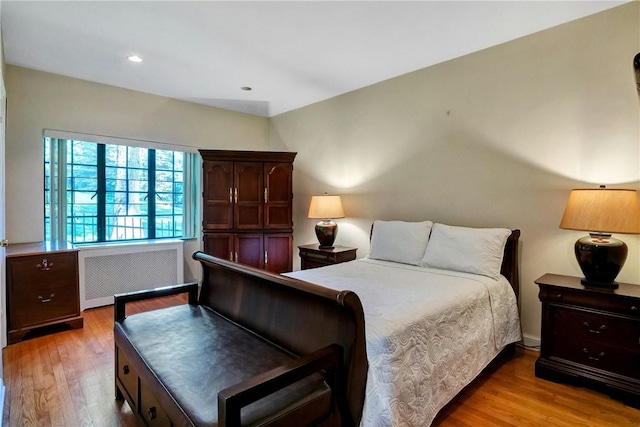 bedroom with light hardwood / wood-style floors and radiator heating unit