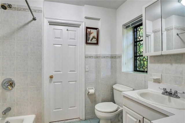 full bathroom with vanity, tiled shower / bath, tile patterned flooring, toilet, and tile walls