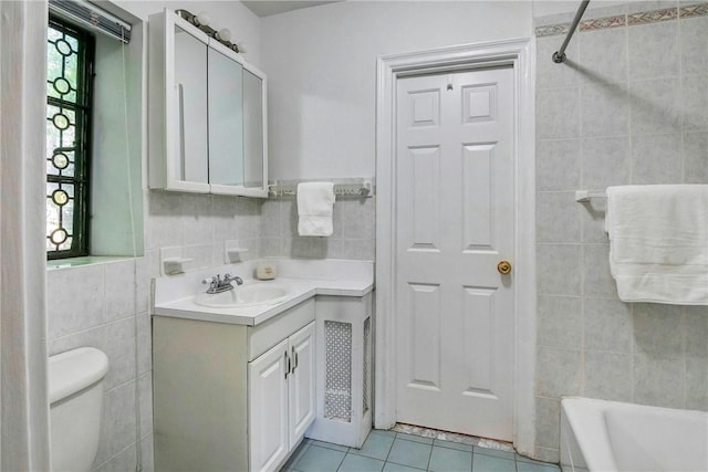 full bathroom with tiled shower / bath combo, tile patterned flooring, toilet, vanity, and tile walls