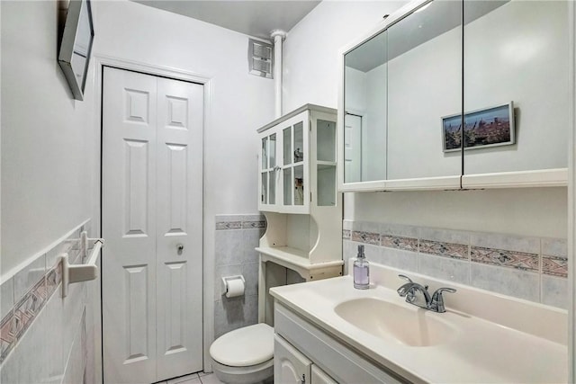 bathroom with tile patterned flooring, vanity, toilet, and tile walls