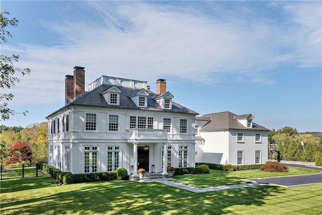 colonial-style house featuring a balcony and a front yard