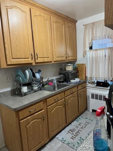 kitchen with radiator heating unit, backsplash, light tile patterned floors, and sink