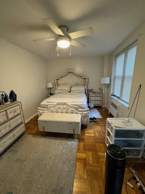 bedroom featuring radiator heating unit, dark parquet floors, and ceiling fan