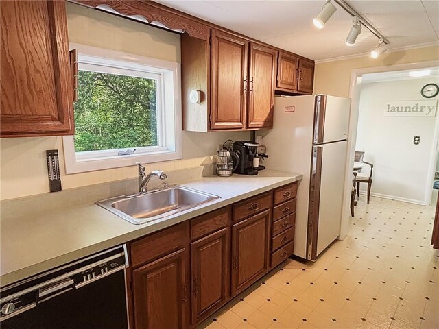 kitchen with dishwasher, sink, white refrigerator, track lighting, and ornamental molding