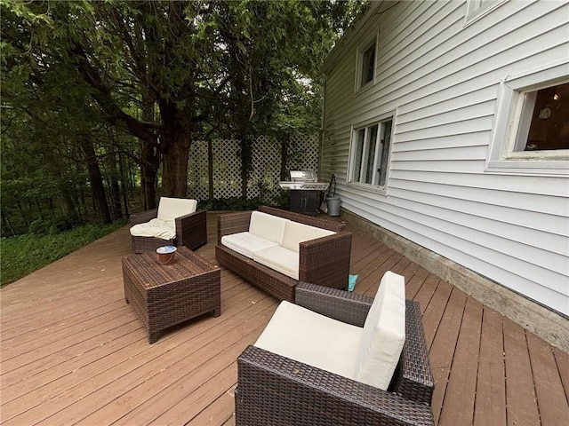 wooden terrace with an outdoor living space and area for grilling