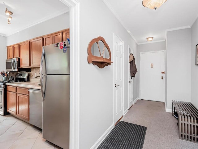 interior space featuring decorative backsplash, crown molding, light tile patterned floors, and stainless steel appliances