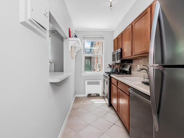 kitchen featuring sink, tasteful backsplash, light tile patterned flooring, radiator heating unit, and stainless steel appliances