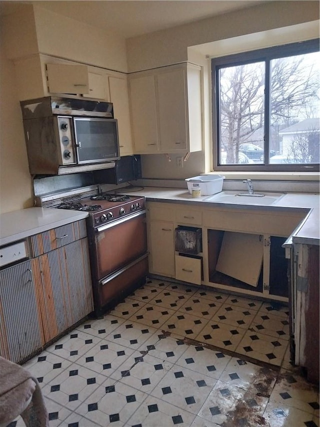 kitchen with gas stove, white cabinetry, and sink